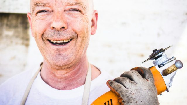 man holding orange angle grinder